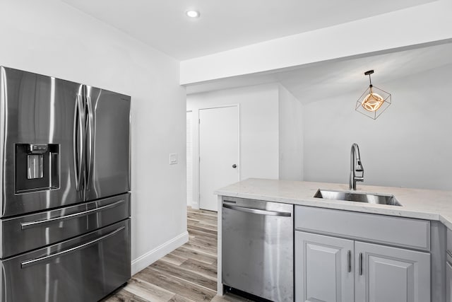 kitchen featuring gray cabinets, sink, hanging light fixtures, appliances with stainless steel finishes, and hardwood / wood-style flooring