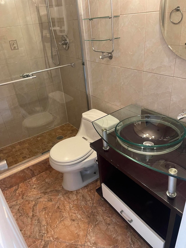 bathroom featuring walk in shower, vanity, toilet, and tile walls