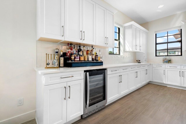 kitchen featuring white cabinetry, tasteful backsplash, light wood-type flooring, and beverage cooler