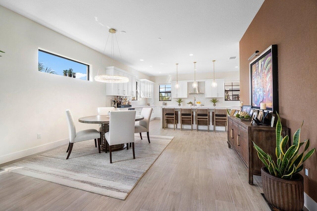 dining room featuring a chandelier, light hardwood / wood-style floors, and a healthy amount of sunlight