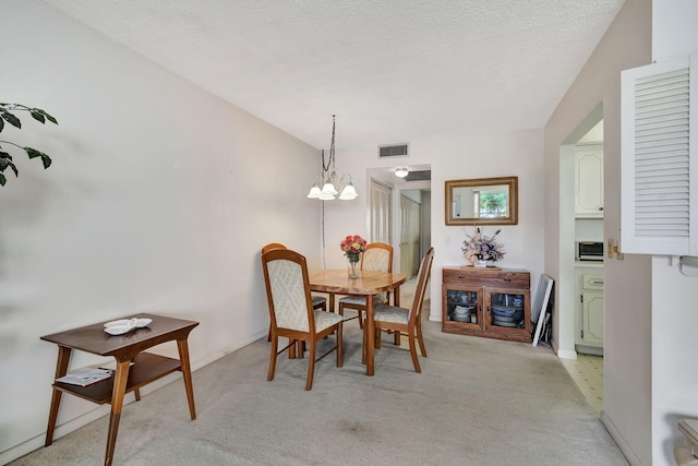 carpeted dining space featuring a textured ceiling and an inviting chandelier