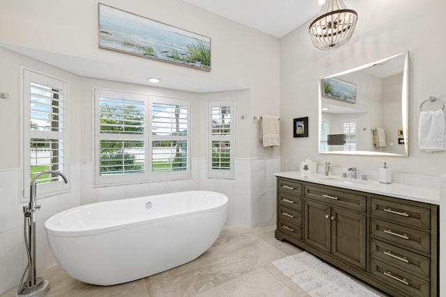 bathroom with tile patterned flooring, a bathtub, a wealth of natural light, vanity, and tile walls