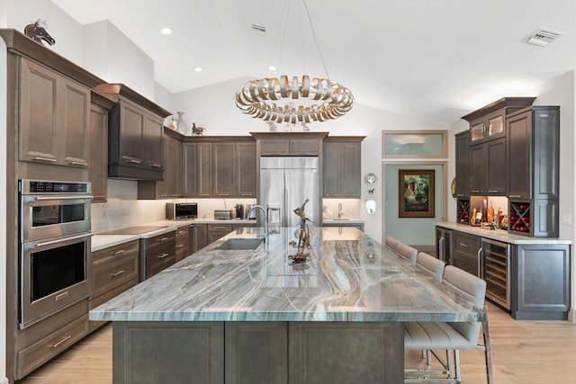 kitchen featuring wine cooler, lofted ceiling, a large island with sink, and stainless steel appliances