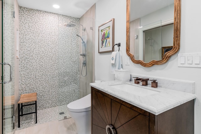 bathroom with toilet, a shower with shower door, vanity, and tile patterned flooring