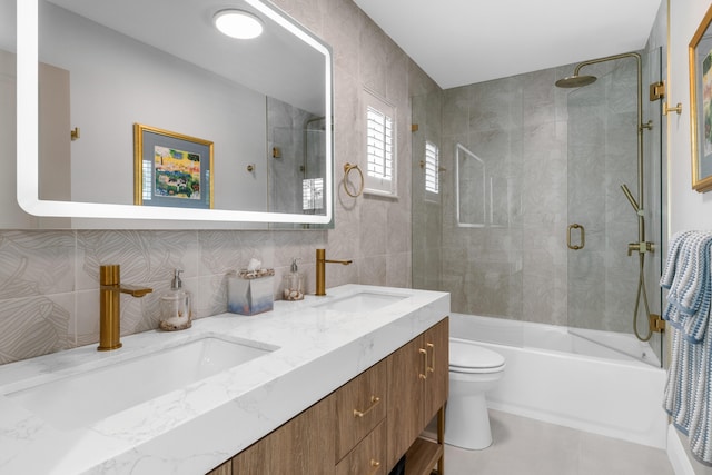 full bathroom featuring vanity, toilet, tile walls, and shower / bath combination with glass door