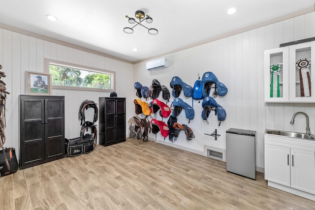 miscellaneous room with an AC wall unit, sink, light hardwood / wood-style floors, and wooden walls