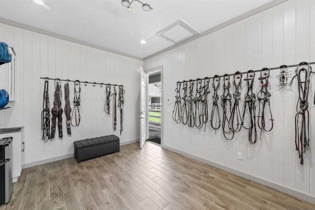 misc room with light hardwood / wood-style flooring, wooden walls, and crown molding