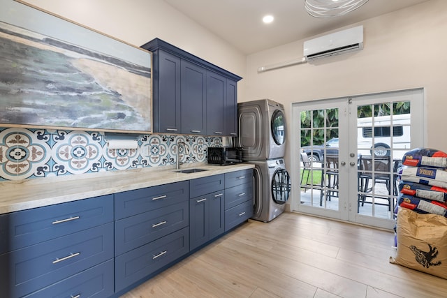 kitchen featuring a wall mounted AC, backsplash, light hardwood / wood-style floors, french doors, and stacked washer / dryer