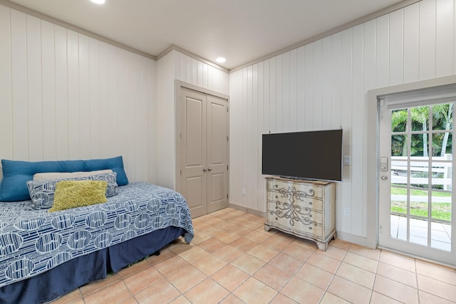 bedroom with a closet, tile patterned floors, access to outside, and wooden walls