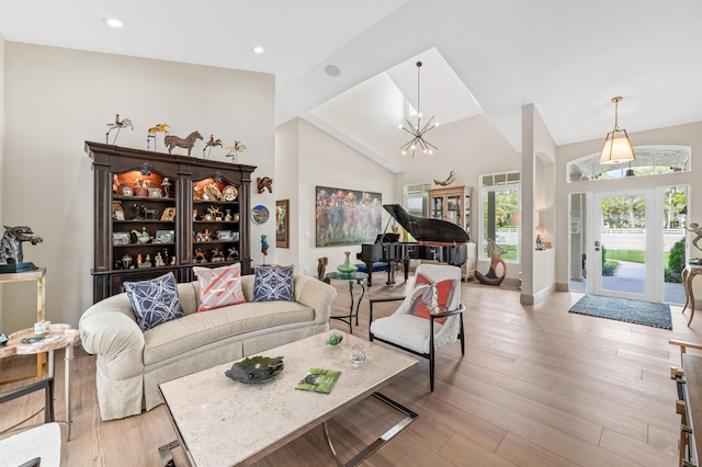 living room with light hardwood / wood-style floors, a notable chandelier, and high vaulted ceiling