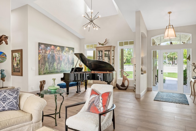 foyer entrance with high vaulted ceiling, light hardwood / wood-style flooring, and an inviting chandelier