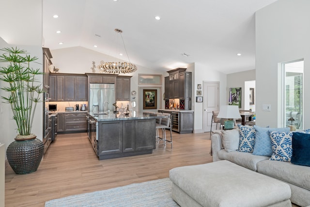 living room featuring sink, wine cooler, high vaulted ceiling, and light hardwood / wood-style flooring