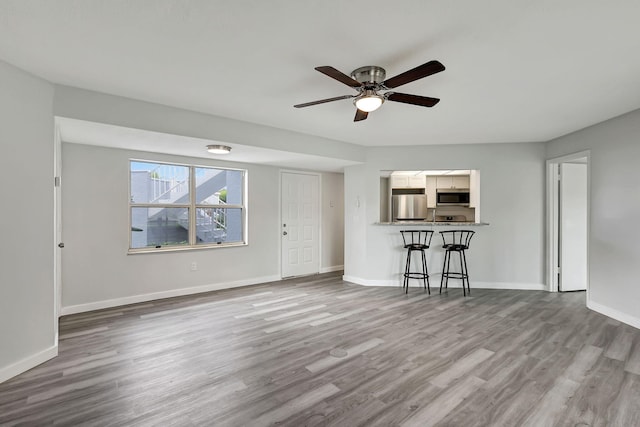 unfurnished living room featuring ceiling fan and hardwood / wood-style flooring