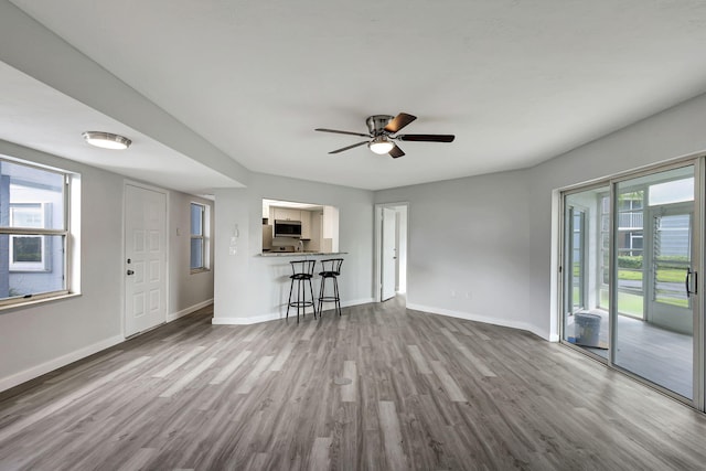 3200 SE Aster Ln Unit S-102, Stuart, FL 34994 - unfurnished living room featuring wood finished floors, baseboards, plenty of natural light, and a ceiling fan