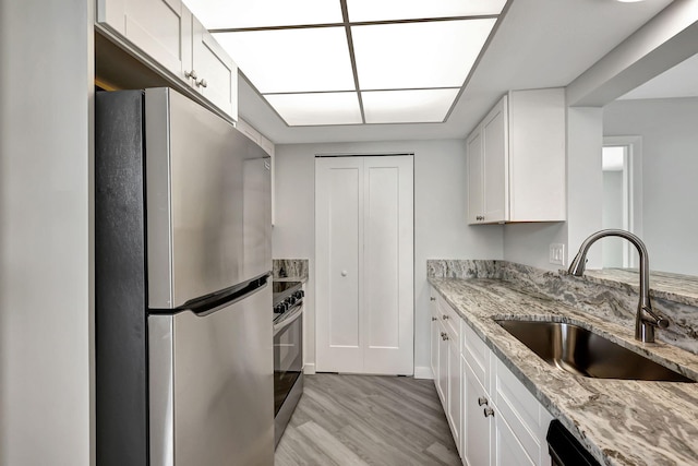 3200 SE Aster Ln Unit S-102, Stuart, FL 34994 - kitchen featuring stainless steel appliances, a sink, light wood-type flooring, and white cabinetry