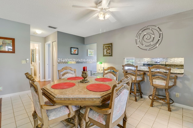 dining room featuring a textured ceiling, light tile patterned floors, and ceiling fan