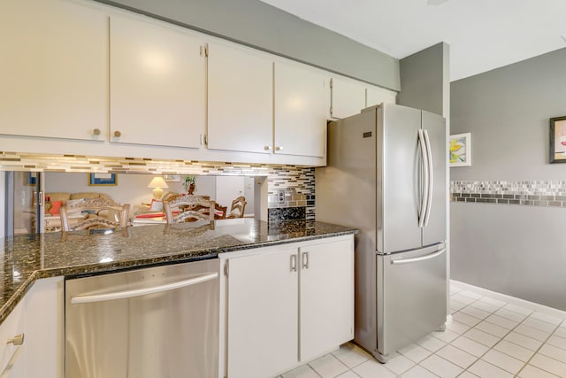 kitchen with appliances with stainless steel finishes, white cabinets, dark stone countertops, and light tile patterned floors