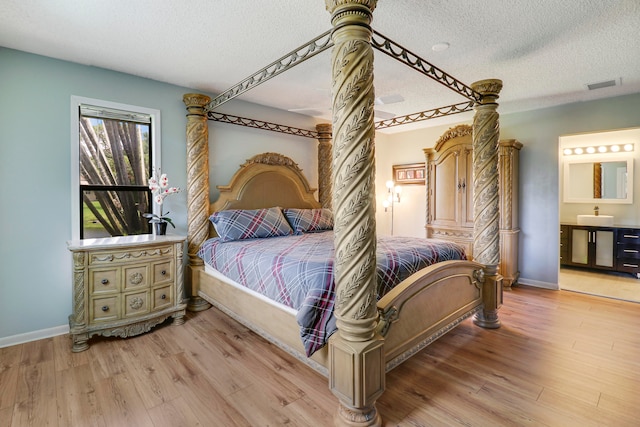 bedroom featuring a textured ceiling, ensuite bathroom, and light wood-type flooring