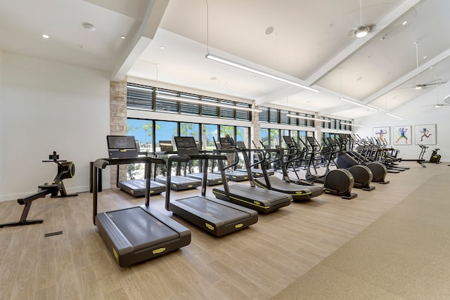 workout area featuring ceiling fan, hardwood / wood-style flooring, and a towering ceiling