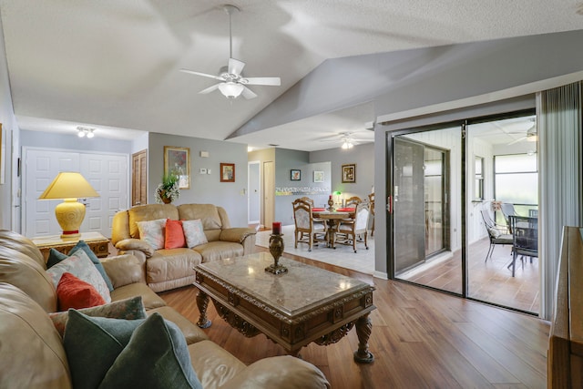 living room with ceiling fan, vaulted ceiling, and light wood-type flooring