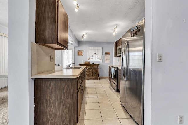 kitchen featuring light tile patterned floors, a textured ceiling, appliances with stainless steel finishes, and dark brown cabinets