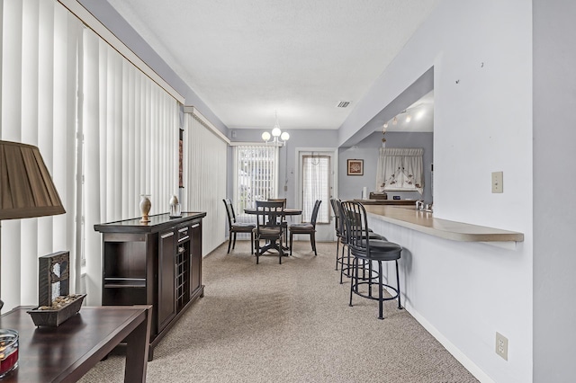 dining space with light carpet and a notable chandelier