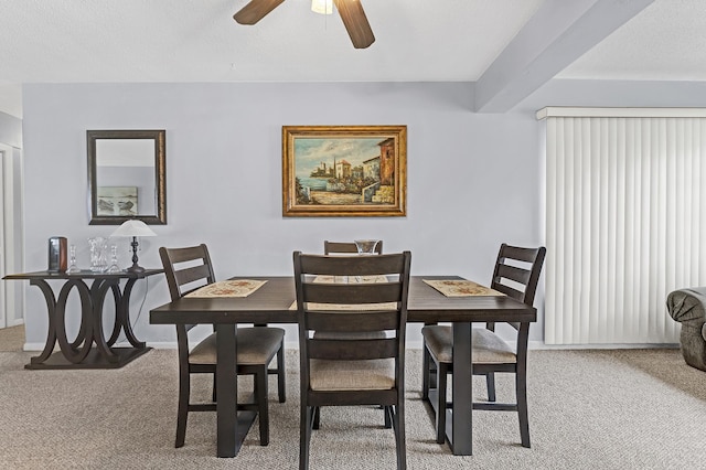 dining room with ceiling fan, light carpet, and beamed ceiling