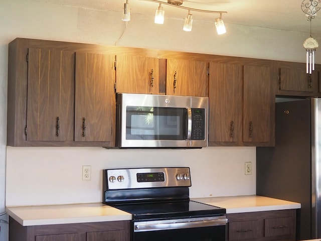 kitchen featuring light countertops, appliances with stainless steel finishes, and brown cabinetry