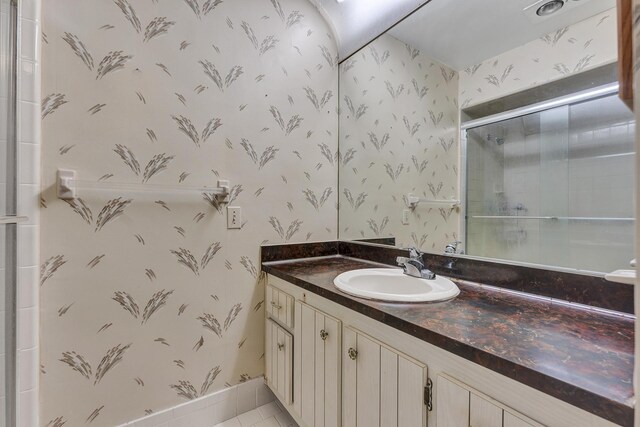bathroom with vanity, tile patterned flooring, tiled shower, and wallpapered walls