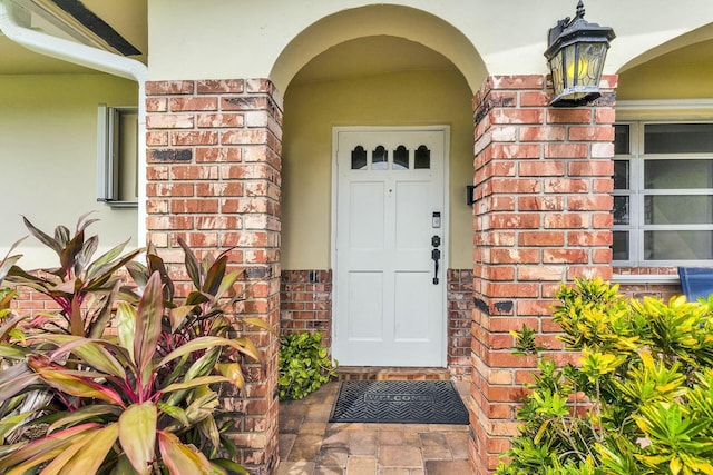 entrance to property featuring brick siding and stucco siding