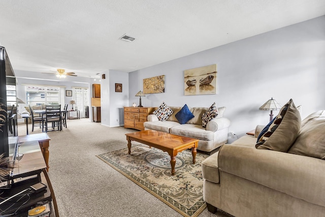 living room featuring ceiling fan, a textured ceiling, and carpet flooring