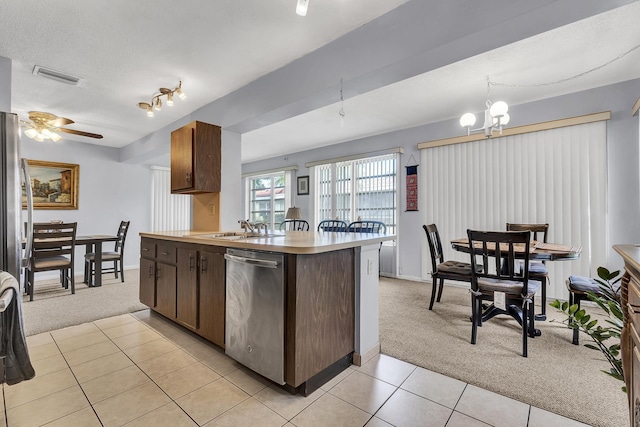 kitchen featuring ceiling fan with notable chandelier, light carpet, sink, kitchen peninsula, and stainless steel dishwasher