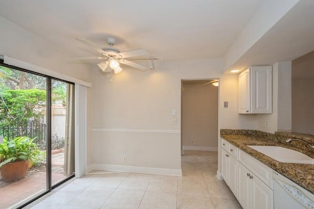 kitchen featuring dark stone countertops, sink, white cabinetry, light tile patterned floors, and dishwasher