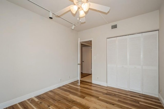 unfurnished bedroom with ceiling fan, a closet, and wood-type flooring