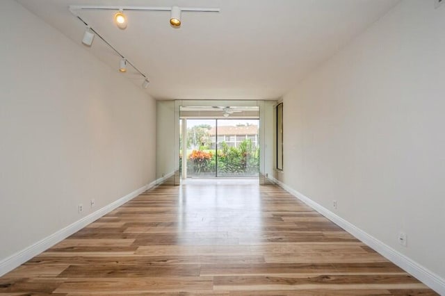 empty room featuring track lighting and light hardwood / wood-style flooring