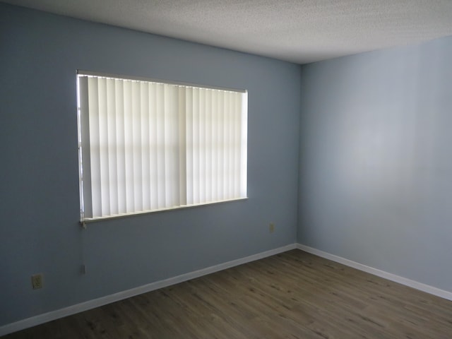 spare room featuring hardwood / wood-style flooring and a textured ceiling