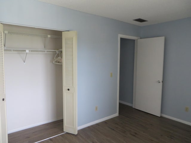 unfurnished bedroom with a closet and dark hardwood / wood-style flooring