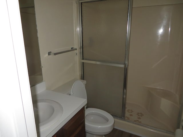 bathroom with hardwood / wood-style floors, vanity, a shower with shower door, and toilet