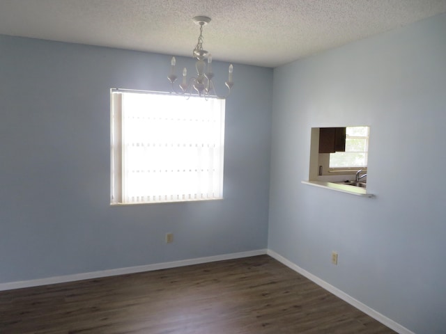 empty room featuring a textured ceiling, a chandelier, and dark hardwood / wood-style flooring