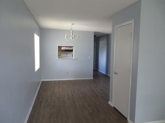 unfurnished room featuring a notable chandelier and dark wood-type flooring