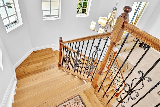 stairway featuring wood-type flooring and an inviting chandelier