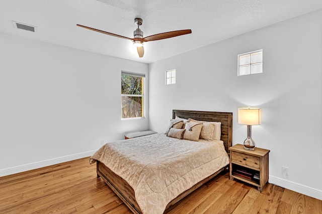 bedroom with light hardwood / wood-style floors, a textured ceiling, and ceiling fan