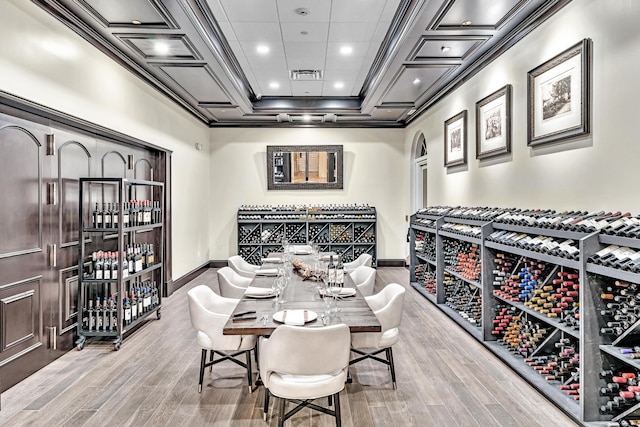 wine area with light hardwood / wood-style flooring, ornamental molding, and coffered ceiling