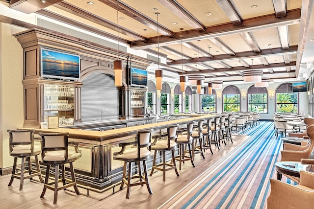 bar with light hardwood / wood-style floors and decorative light fixtures