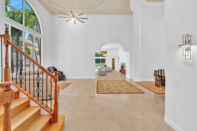 foyer entrance with a high ceiling, a healthy amount of sunlight, and ceiling fan