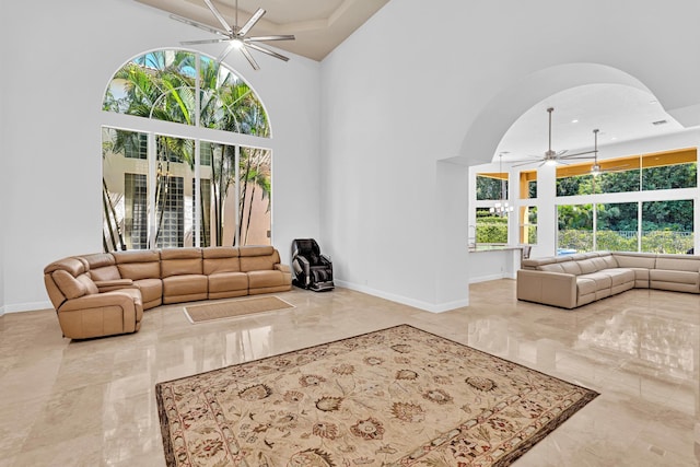 living room featuring a towering ceiling, a healthy amount of sunlight, and ceiling fan