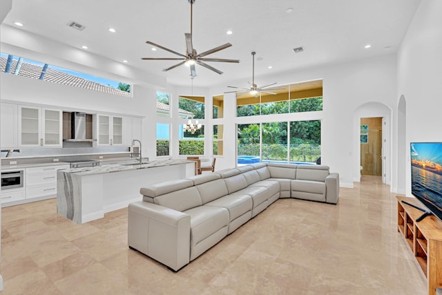 living room with sink, a high ceiling, and ceiling fan with notable chandelier