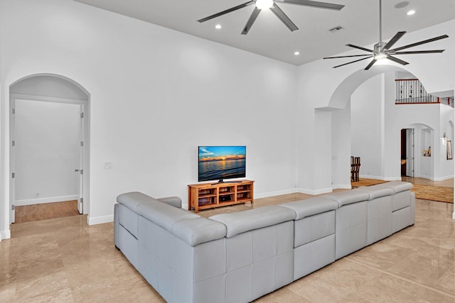 living room with a towering ceiling and ceiling fan