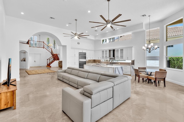 living room featuring ceiling fan with notable chandelier, a high ceiling, and a wealth of natural light