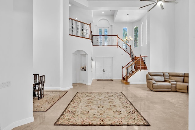 foyer with ceiling fan with notable chandelier and a towering ceiling